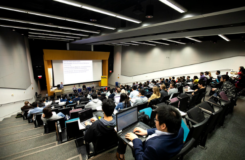 Many students taking class in a large auditorium