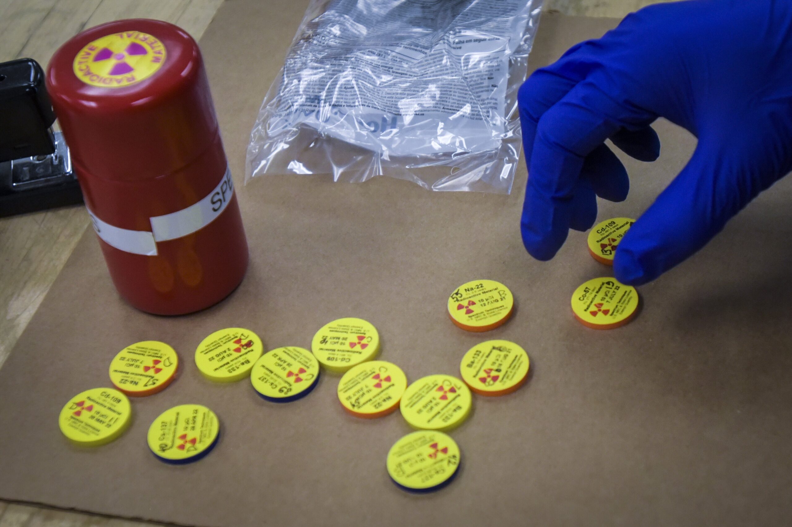 Gloved hand examining small disks with radioactive labels