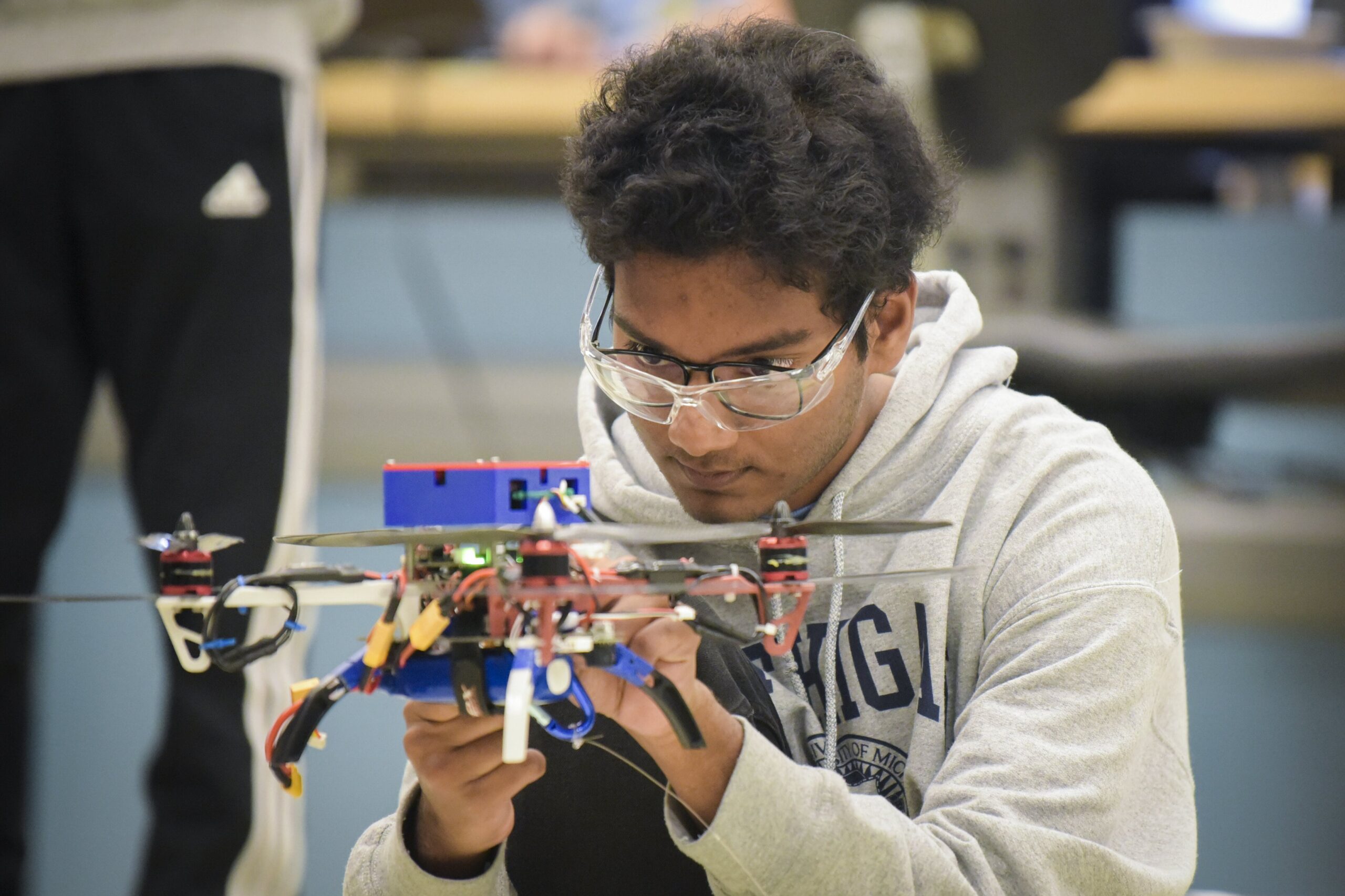 Student in goggles holding drone and adjusting parts