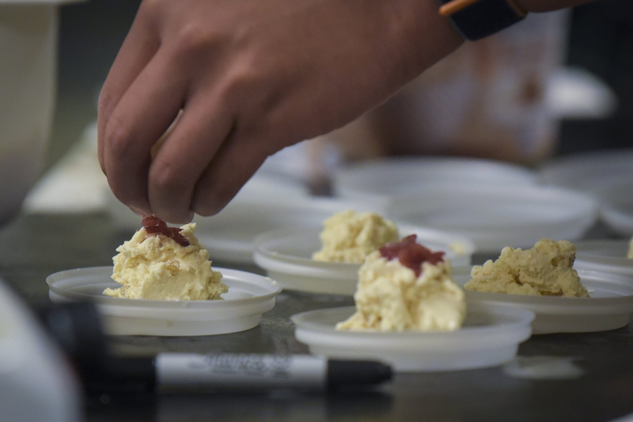 Hand placing red garnish on top of finished food product