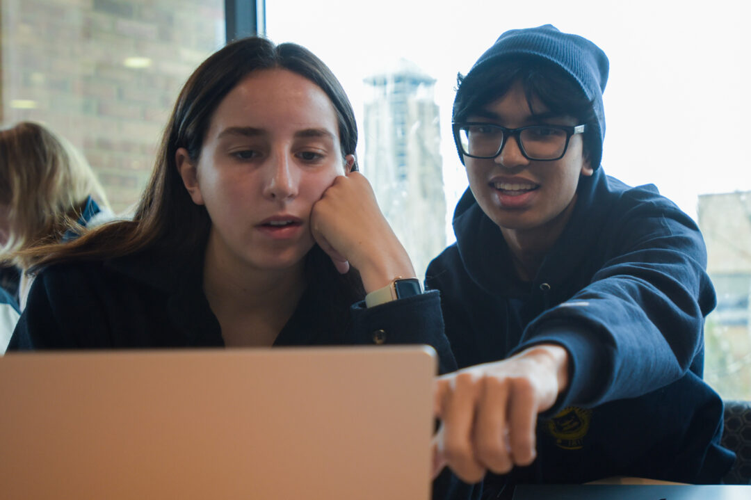 two students discussing assignment on laptop
