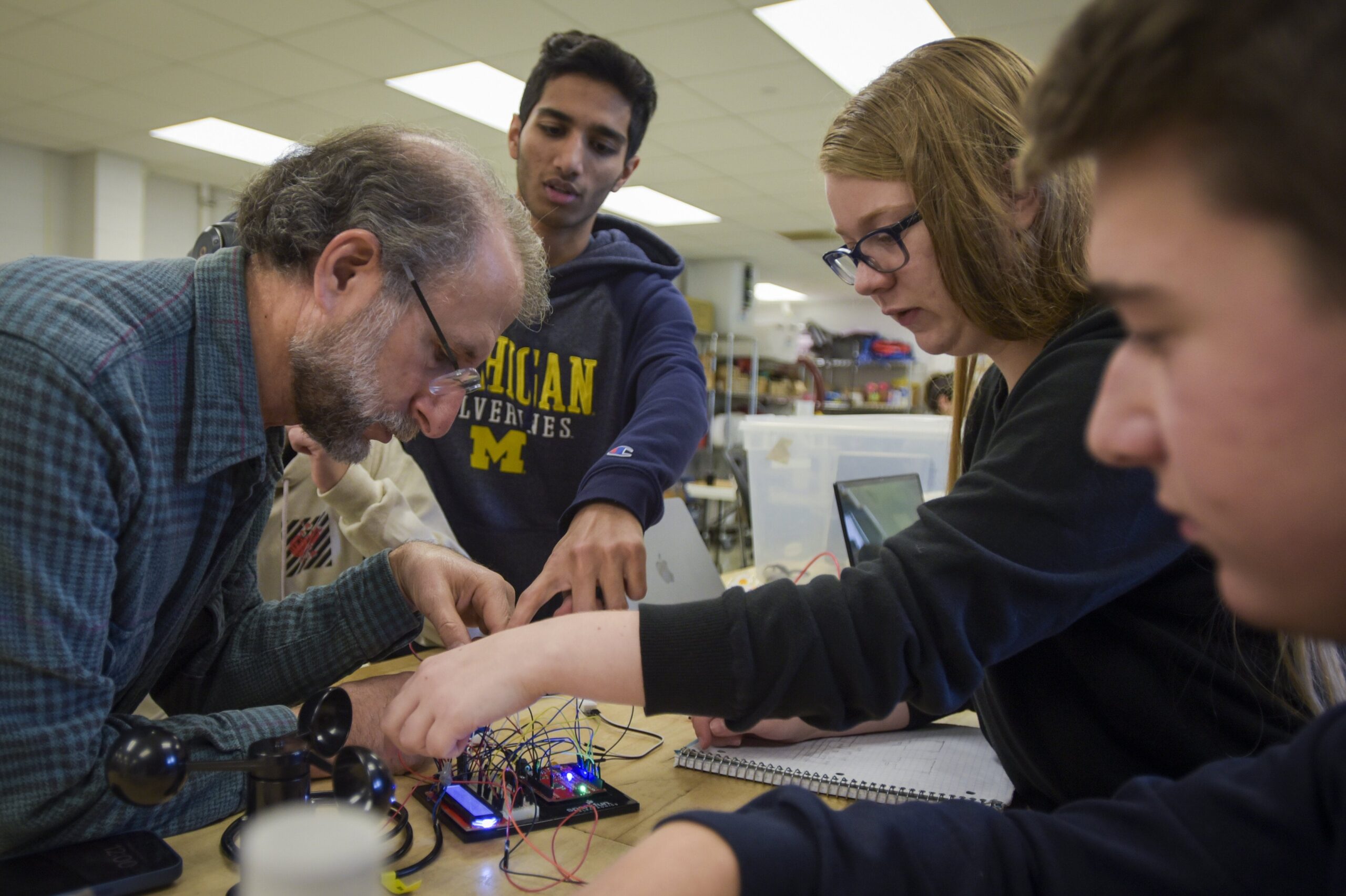 Instructor and three students working on circuit board together