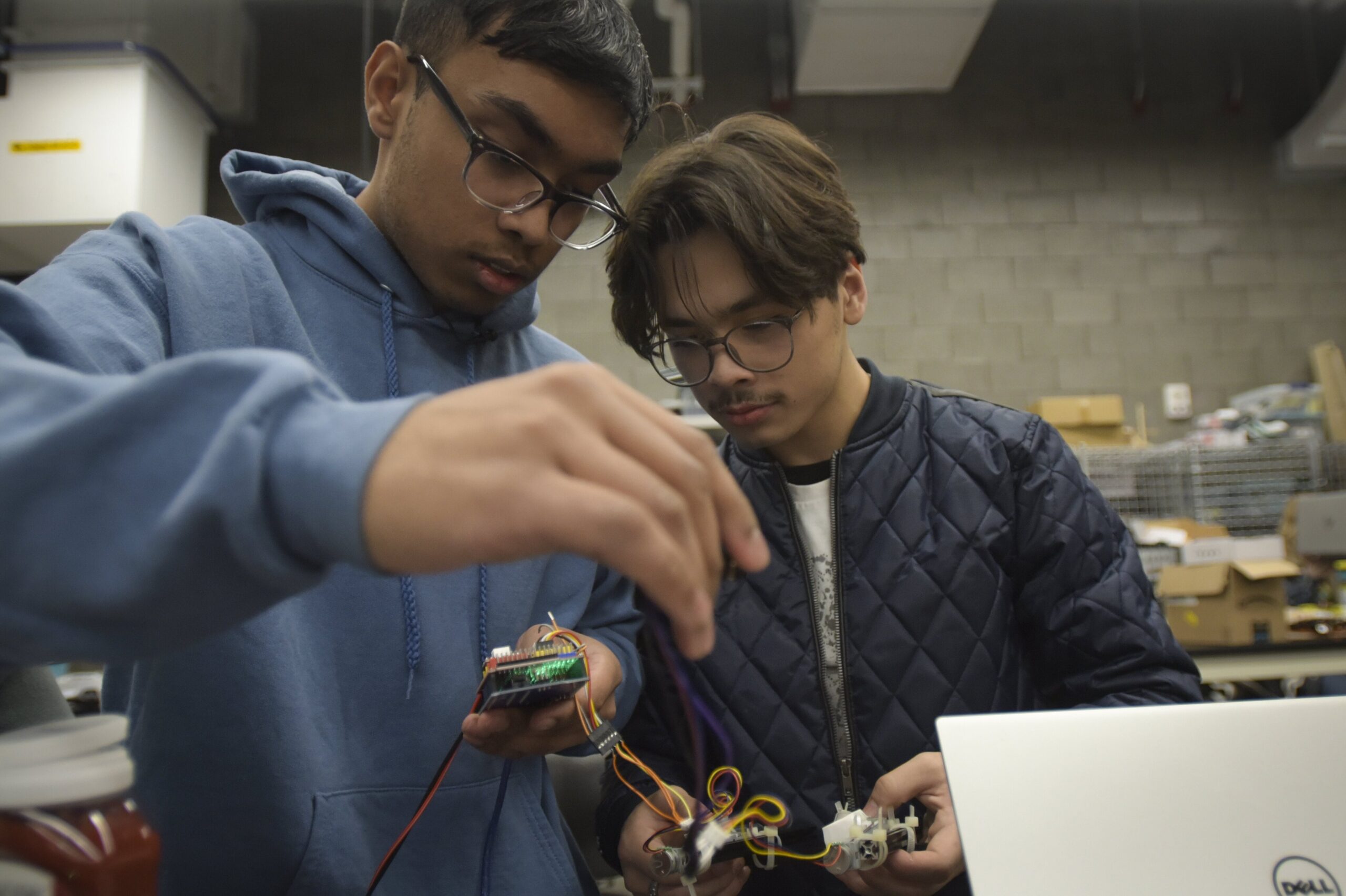 Two students holding wired parts together