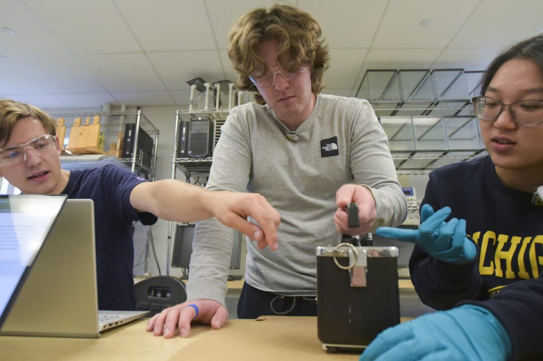 three students testing lab equipment