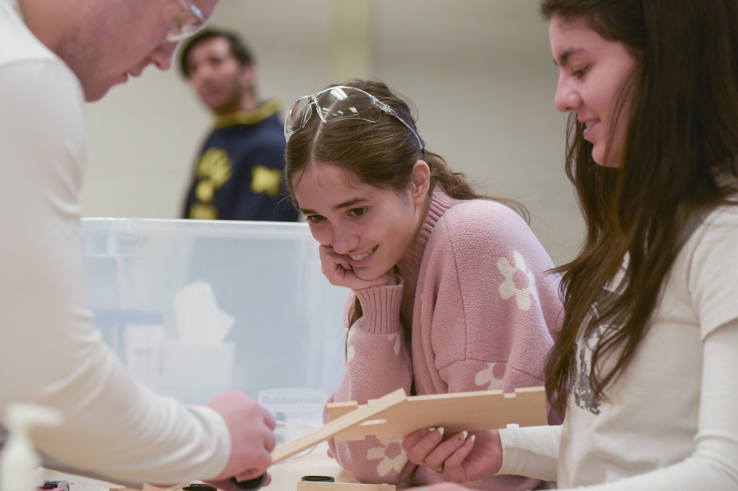 Student smiling at group members assembling wooden parts